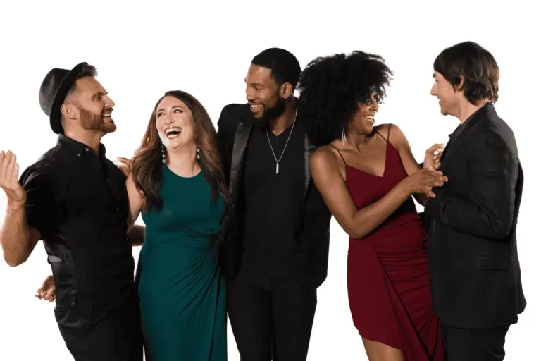 Group of five people laughing and interacting together in a studio setting.