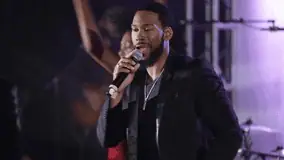 Male singer performing confidently onstage while holding a microphone.