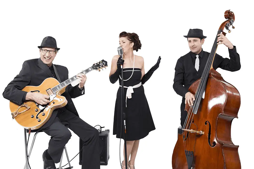 Jazz trio performing with a guitarist, vocalist, and upright bassist against a clean white background.