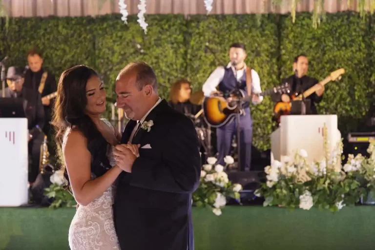 Bride and groom sharing a romantic first dance with a live band performing in the background.